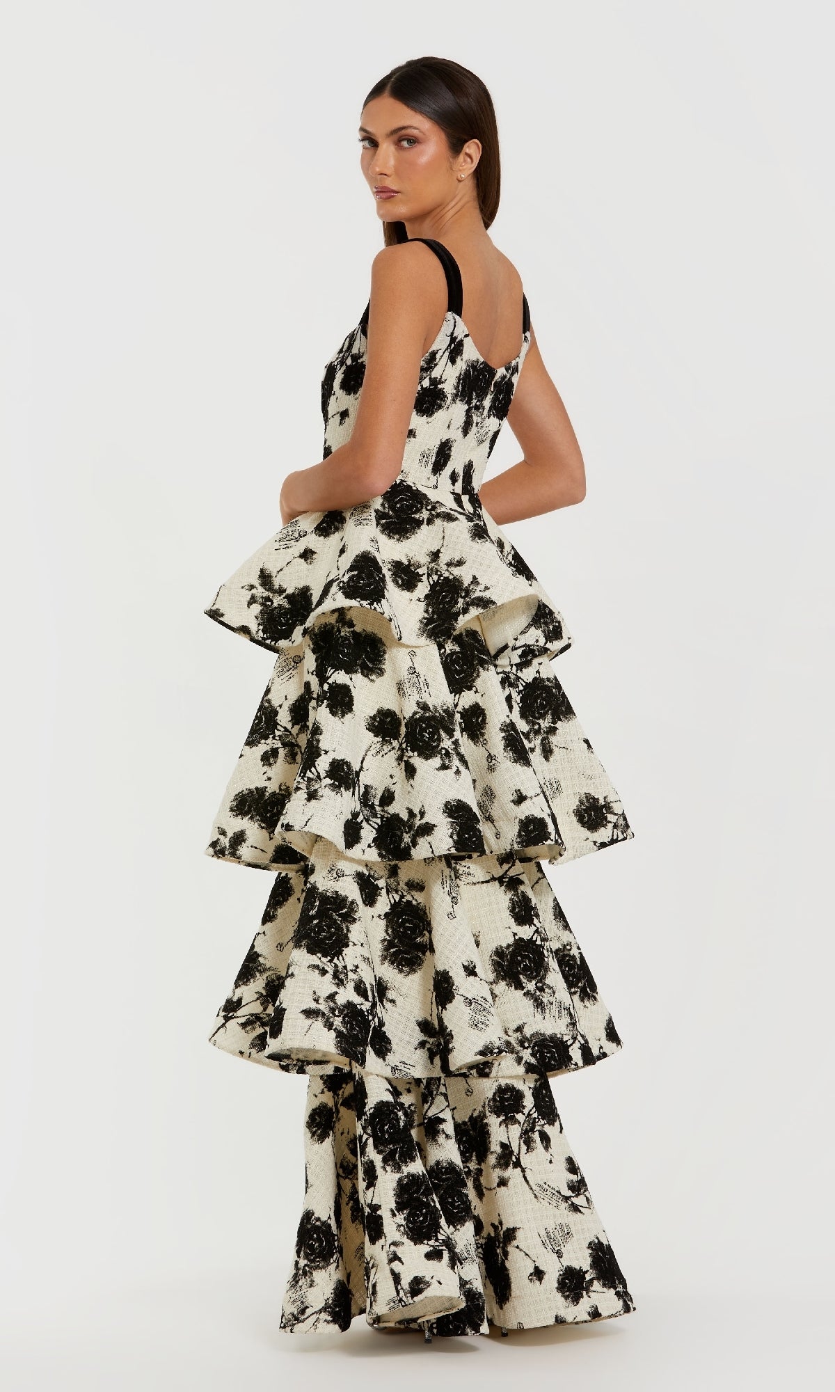 Woman wearing a black and white floral tiered dress on a white background
